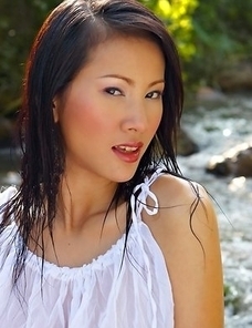Nancy Ho lies on the middle of a stream and she shows what she can do. She has a white top that is nice and wet from the water.