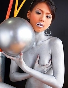 Naomi Chatee sits on a sofa completely covered in silver. This babe has an amazing body and the paint is just a masking agent for her sexiness.